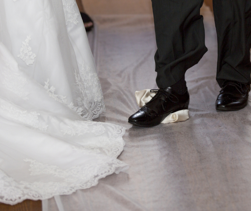 Groom breaks glass at Jewish wedding. Bride stands alongside. View is from the knee down